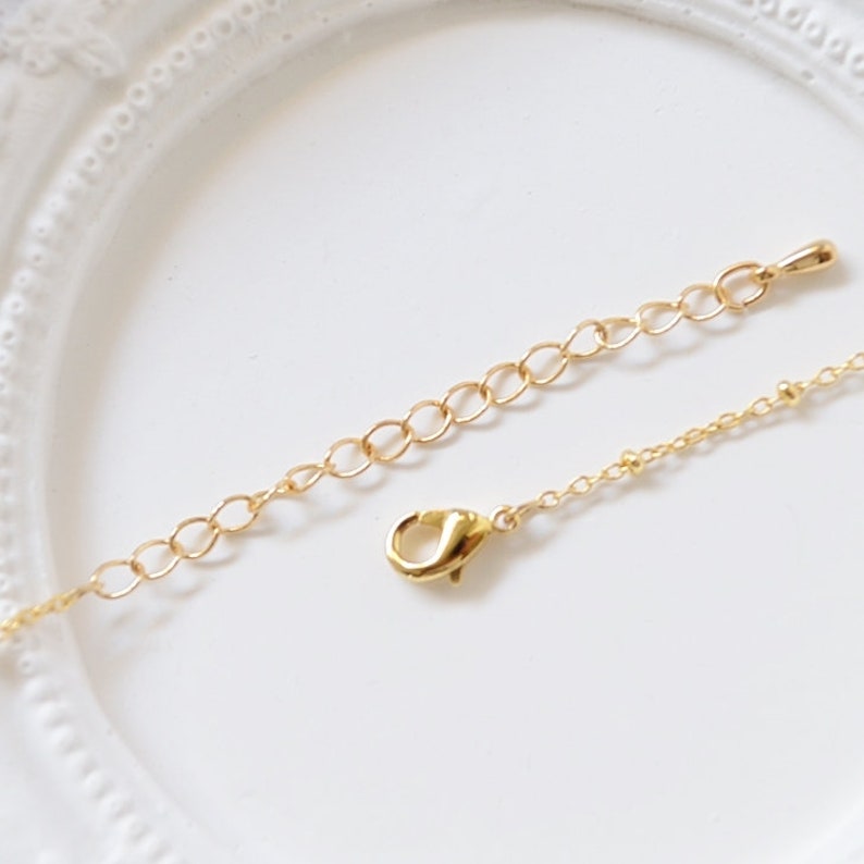 May include: A gold chain necklace with a lobster clasp closure. The chain is made of small, round links.