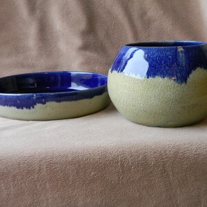May include: Two ceramic bowls, one round and one oval, with a blue glaze on top and a light beige glaze on the bottom.