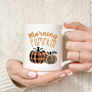 May include: White ceramic mug with a black and orange plaid pumpkin and a leopard print pumpkin. The mug has the text "Morning Pumpkin" printed on it.