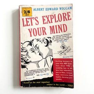 以下が含まれることがあります： アルバート・エドワード・ウィガム著の「Let's Explore Your Mind」というタイトルのヴィンテージペーパーバック。表紙には、キスをしているカップルの白黒イラストが描かれています。本は赤と白の配色で、テキストとイラストが使用されています。