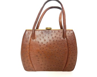 May include: A brown leather handbag with a textured surface and two curved handles. The bag has a gold-colored clasp and a rounded shape. The handbag is a vintage style.