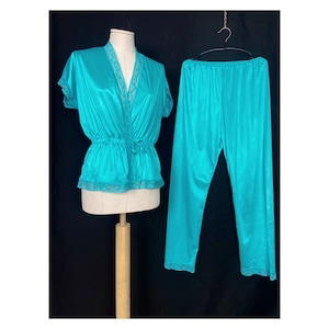May include: A turquoise satin pajama set with lace trim. The top has a V-neck and short sleeves. The pants have a straight leg.