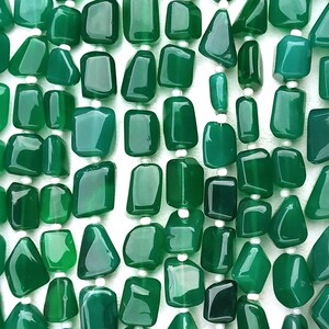 May include: A strand of green agate gemstone beads, each bead is a unique, irregular shape. The beads are strung on white thread.