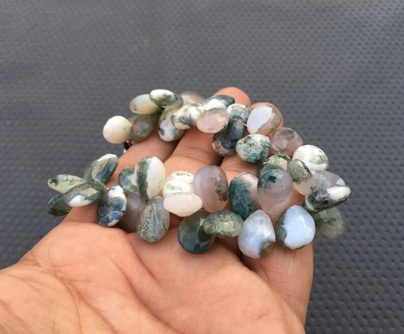 May include: A strand of moss agate beads in shades of green, white, and gray. The beads are irregularly shaped and have a natural, polished finish.