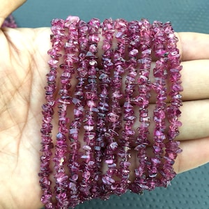 May include: A strand of pink tourmaline chip beads. The beads are small and irregular in shape, and they have a natural, unpolished finish.