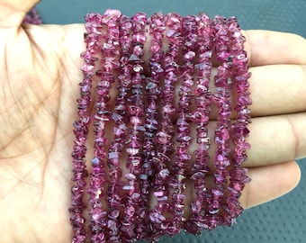 May include: A strand of pink tourmaline chip beads. The beads are small and irregular in shape, and they have a natural, unpolished finish.