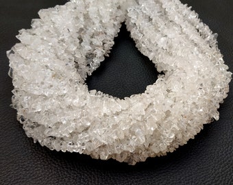 May include: A strand of clear quartz crystal chips, also known as rock crystal, arranged in a circle. The chips are faceted and have a natural, raw look.