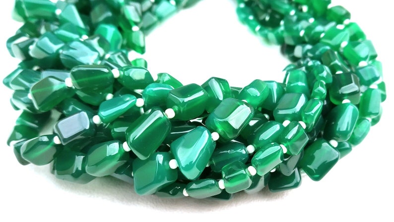 May include: A strand of green agate gemstone beads, each bead is a unique, irregular shape. The beads are polished and have a smooth, glossy finish.