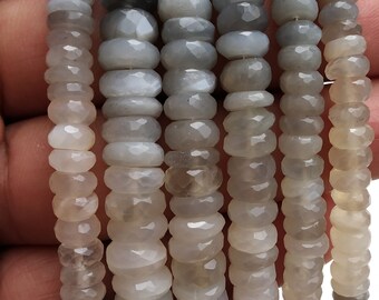 May include: A strand of gray moonstone beads, faceted and round, with a slightly iridescent sheen. The beads are strung on a clear elastic cord and are approximately 6mm in diameter.