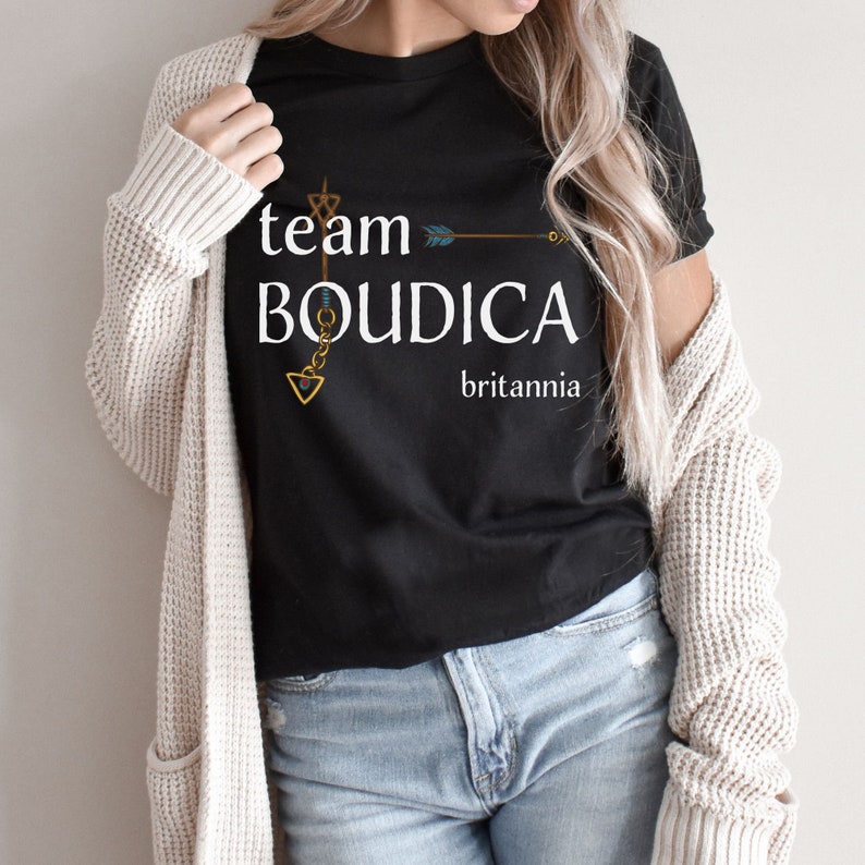Pu&ograve; includere: Maglietta nera con una grafica bianca che dice "team Boudica britannia" con un design a freccia dorata e catena.