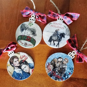 Può includere: Quattro sfere di Natale rotonde in legno con fiocchi di nastro rosso e nero a quadri. Ogni sfera presenta un'immagine e un testo diversi. Una sfera dice "Buon Natale" e presenta una coppia che si bacia. Un'altra sfera dice "Buone Feste" e presenta una coppia a cavallo. La terza sfera dice "Hellig Jul" e presenta una coppia che si abbraccia. La quarta sfera dice "Buon Natale" e presenta una coppia che si abbraccia.