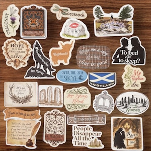 May include: A selection of decorative stickers with diverse designs and text. The stickers showcase images of a dragonfly, a wolf, a highland cow, and phrases such as "Over the Sea to Skye" and "Scotland".