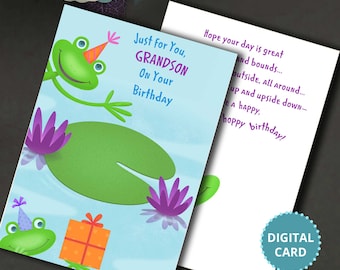 May include: A birthday card featuring a green frog wearing a party hat and holding a gift. The card has a blue background with a green lily pad and purple water lilies. The text on the card reads "Just for You, Grandson On Your Birthday".