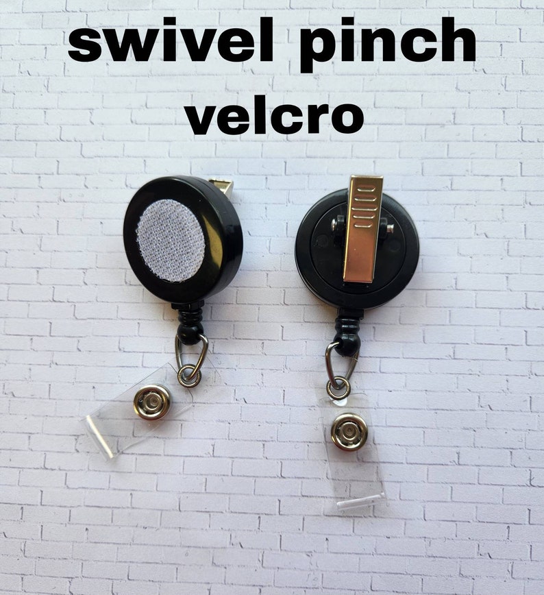 May include: Two black retractable badge reels with swivel clips and clear plastic badge holders. One reel has a velcro attachment and the other has a pinch clip.