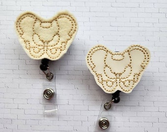 May include: Two white felt anatomical bone-shaped badge holders with gold stitching and black retractable badge reels.