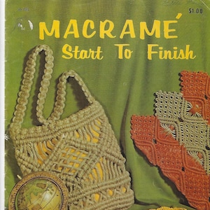 Peut inclure: Un livre intitulé "Macramé' Start To Finish" avec un sac en macramé marron, une ceinture en macramé jaune et un globe terrestre sur un support en bois. La couverture du livre est verte avec le titre en lettres jaunes.