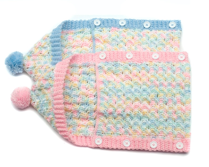 May include: Two crocheted baby hats with pom-poms. The hats are made with a multi-colored yarn in shades of blue, pink, and yellow. The hats have button closures.