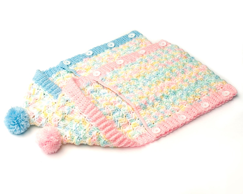 May include: A crocheted baby cardigan and hat set in a pastel rainbow color scheme with white buttons. The cardigan has a button-up front and the hat has a pom-pom on top.