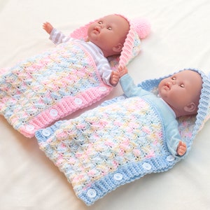 May include: Two crocheted baby sleeping bags with hoods, one pink and one blue, with white buttons. The sleeping bags are made with a textured stitch and have a colorful yarn pattern.