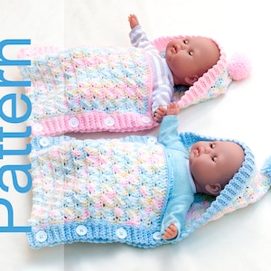 May include: Two crocheted baby sleeping bags with hoods and pom-poms. One is pink and white, the other is blue and white. Both have buttons down the front.