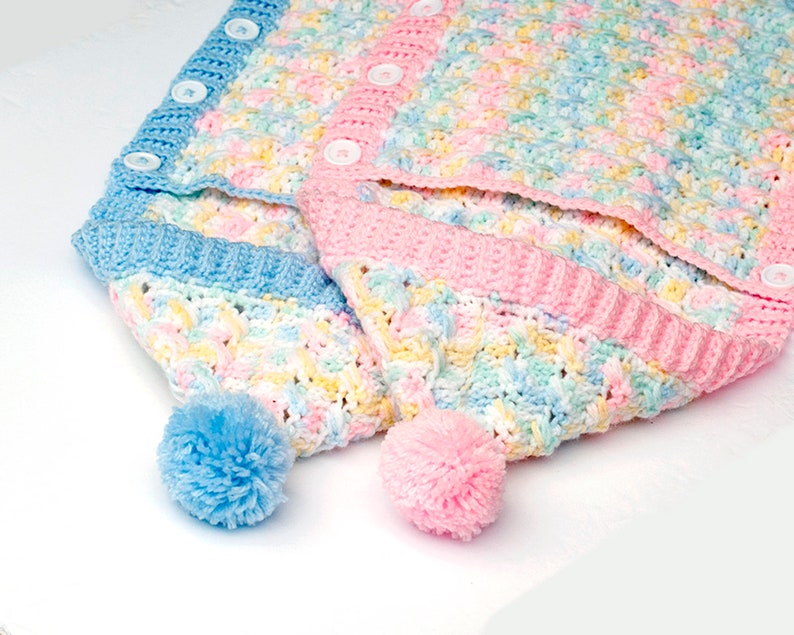 May include: Two crocheted baby hats with pom-poms. One hat is blue and the other is pink. Both hats have a multi-colored pattern.
