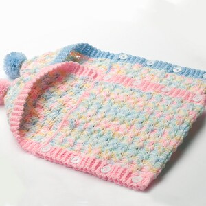 May include: A crocheted baby vest with a hood and pom-poms. The vest is made in a multi-colored yarn with pink, blue, and yellow stripes. The vest has a button closure.