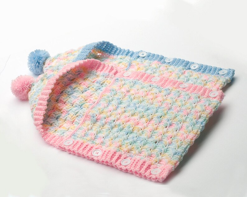 May include: A crocheted baby vest with a hood and pom-poms. The vest is made in a multi-colored yarn with pink, blue, and yellow stripes. The vest has a button closure.