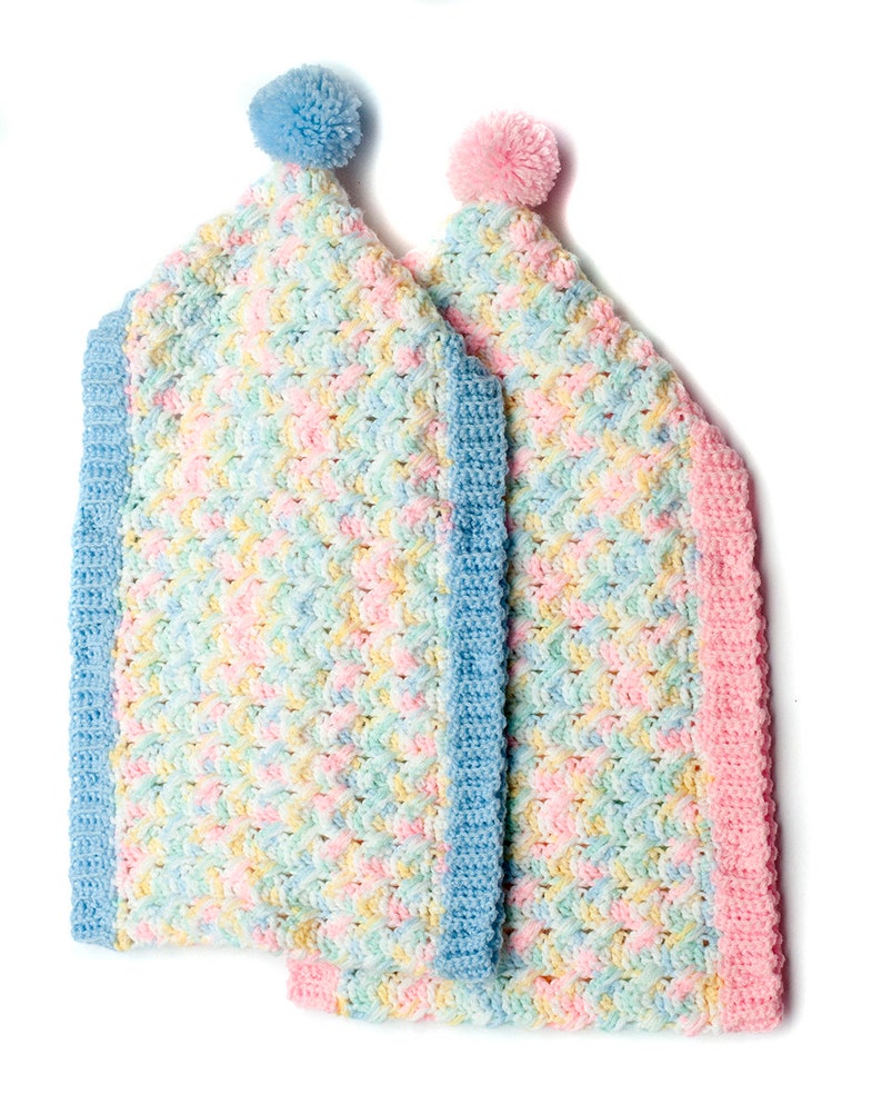 May include: Two crocheted baby blankets with pom-poms. One blanket is blue and pink, the other is pink and yellow.