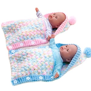 May include: Two crocheted baby sleeping bags with hoods and pom-poms. One is pink with yellow and blue accents, the other is blue with pink and yellow accents.