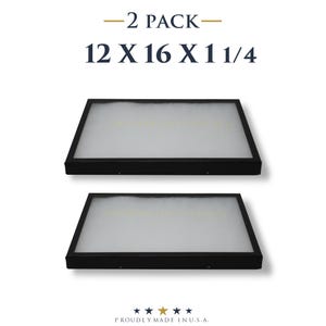 May include: Two black framed rectangular objects with white interiors. The text "-2 PACK-" and "12 X 16 X 1 1/4" is above the objects. The text "PROUDLY MADE IN U.S.A." is below the objects.