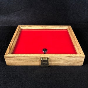 May include: A wooden display case with a red velvet interior and a glass top. The case has a lock and key.
