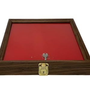 May include: A wooden display case with a red velvet interior and a brass lock. The case is closed and a key is visible in the lock.