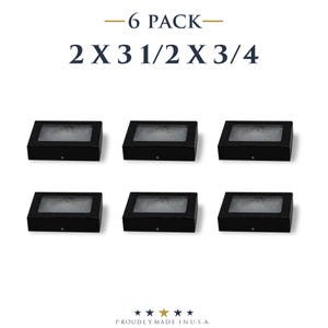 May include: Six black display boxes, each with a rectangular shape and a clear top. The dimensions are 2 x 3 1/2 x 3/4 inches. The text "6 PACK" and the dimensions are displayed at the top. The bottom of the image reads "PROUDLY MADE IN U.S.A."