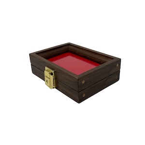 May include: A rectangular wooden display box with a red interior. The box is made of dark brown wood and features a gold-colored latch. The box is designed to showcase small items.