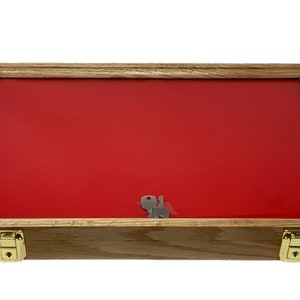May include: A wooden display case with a red velvet interior and two brass locks. The case is closed and has a clear glass top.
