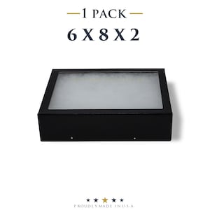 May include: A black rectangular display case with a clear top. The dimensions are 6 x 8 x 2 inches. The text "-1 PACK-" and "6 X 8 X 2" are at the top. The bottom of the image has the text "PROUDLY MADE IN U.S.A." with four stars.
