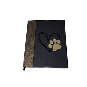 May include: A black and gold journal with a paw print inside a heart design.