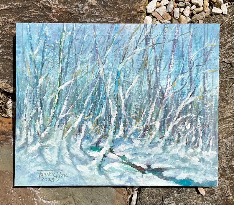 Puede incluir: Una pintura que representa una escena de bosque nevado con &aacute;rboles desnudos y un cielo azul. La pintura est&aacute; firmada "Joukkiel Jou" y fechada "2023".