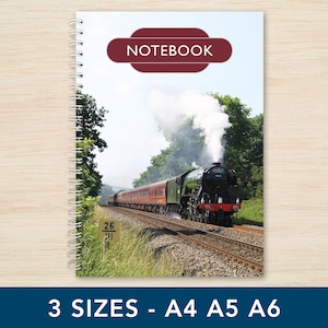 May include: A spiral bound notebook featuring a colourful image of a steam train on the front cover. The train is red and black with white smoke billowing from the chimney. The text "NOTEBOOK" is printed in a red rectangle on the cover.