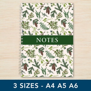 May include: A white spiral bound notebook with a green cover featuring a repeating pattern of pine branches, berries, and pine cones. The cover has the word "NOTES" printed in white on a green banner.
