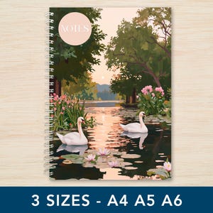 May include: A spiral-bound notebook with a tranquil scene of two swans on a lake, framed by pink flowers and trees. The cover has a pink circle with "NOTES". Available in A4, A5, and A6 sizes.