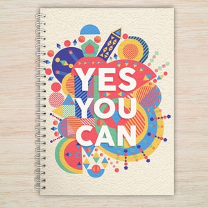 May include: A spiral bound notebook with a colourful geometric design and the text "YES YOU CAN" in white letters.
