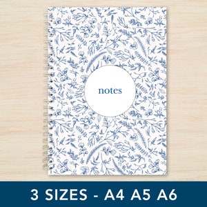 May include: A white spiral bound notebook with a blue floral pattern and the word "notes" in a circle on the front cover.
