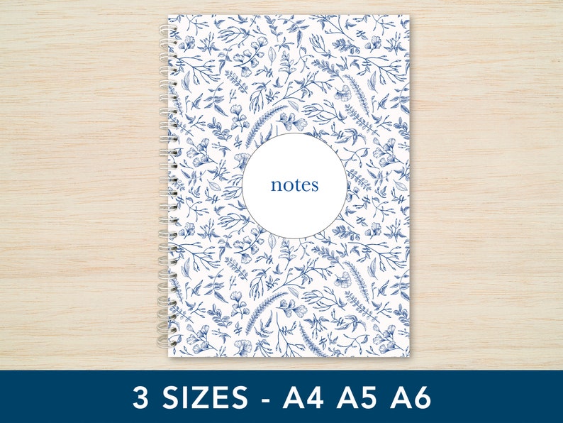 May include: A white spiral bound notebook with a blue floral pattern and the word "notes" in a circle on the front cover.