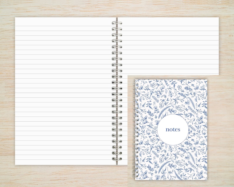 May include: A white spiral bound notebook with lined pages and a blue floral design on the cover. The cover has a circle with the word "notes" inside.
