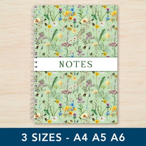 May include: A green spiral bound notebook with a floral pattern featuring yellow, white, and blue flowers and bees. The notebook has the word "NOTES" printed on the front cover.