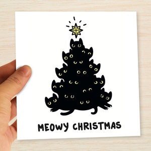Pu&ograve; includere: Biglietto di auguri bianco con un disegno di albero di Natale fatto di gatti neri. L'albero &egrave; composto da sagome di gatti neri con occhi gialli, sormontato da una stella gialla. La scritta "MEOWY CHRISTMAS" &egrave; stampata sotto.