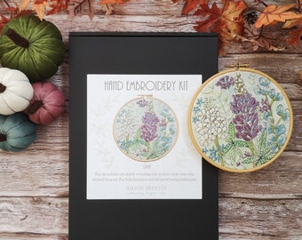 May include: A hand embroidery kit with a black box, a wooden embroidery hoop with a floral design, and the text "HAND EMBROIDERY KIT" and "LUPITT".
