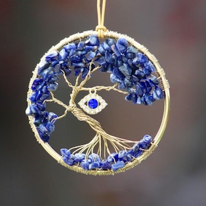 May include: A gold wire tree of life with blue lapis lazuli stones and a blue evil eye charm hanging from the bottom.