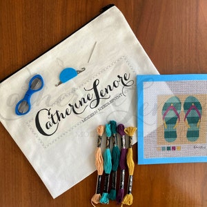 May include: A needlepoint kit with a white canvas bag, blue scissors, a needle threader, embroidery floss in various colors, and a blue canvas with a design of two green and blue flip flops.